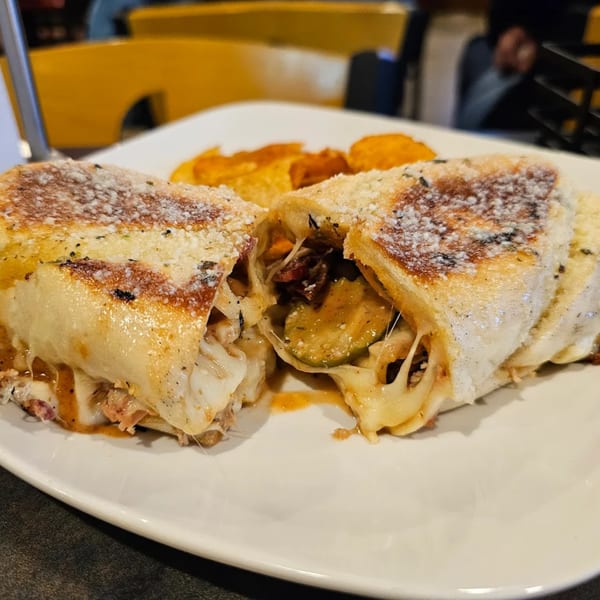 A calzone from Dontae's Highland Pizza Parlor, cut in half, revealing melted cheese and fillings.