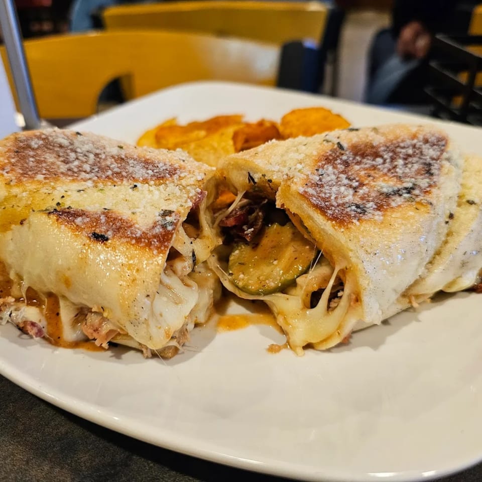 A calzone from Dontae's Highland Pizza Parlor, cut in half, revealing melted cheese and fillings.